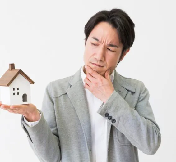A man holding a miniature hose and pondering reasons to sell his current home.